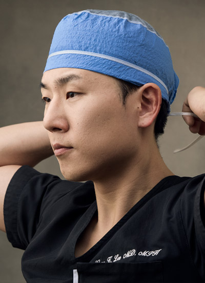 black and white photo of La Môem Plastic Surgery founder Dr. Gene K. Lee, MD, MPH wearing scrubs in Beverly Hills