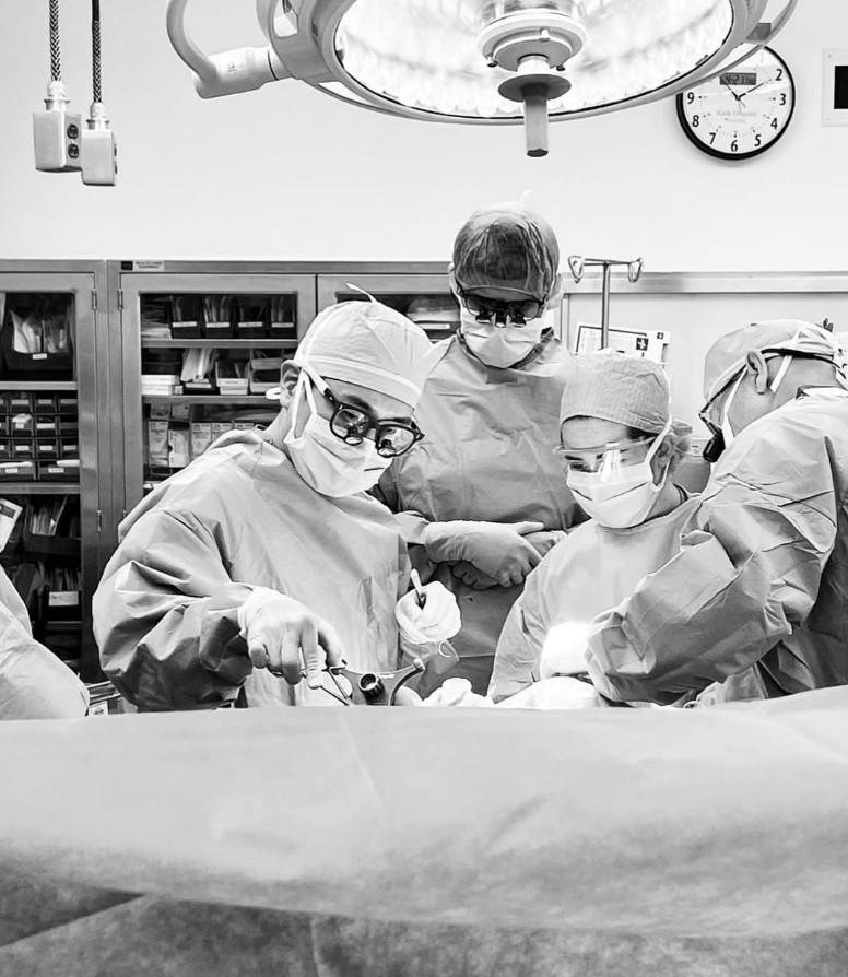 black and white photo of Dr. Gene K. Lee operating on patient with medical staff